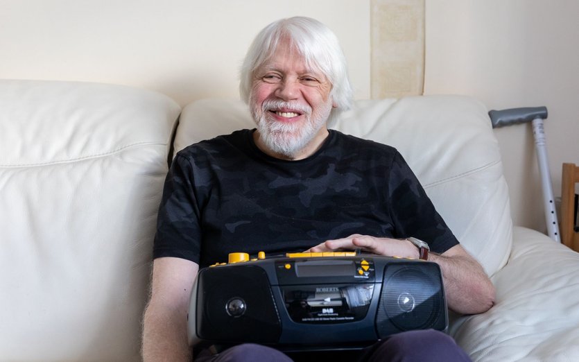 Elderly man using British Wireless-provided audio device
