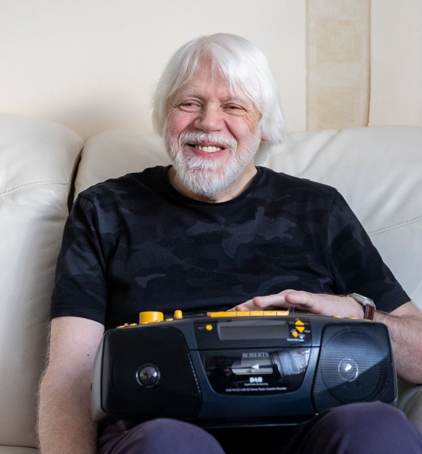 Elderly man using British Wireless-provided audio device