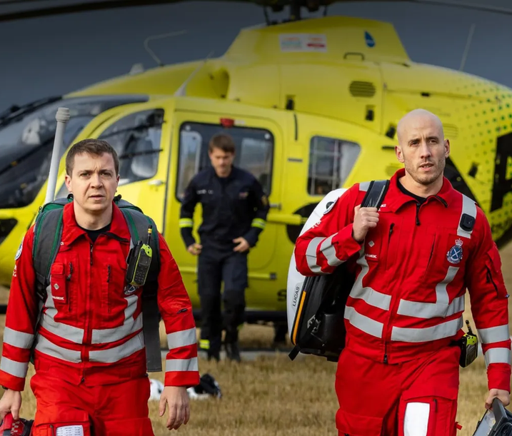Two Scotland’s Charity Air Ambulance crew members in red uniforms walking from a yellow helicopter, used as a small case study image.