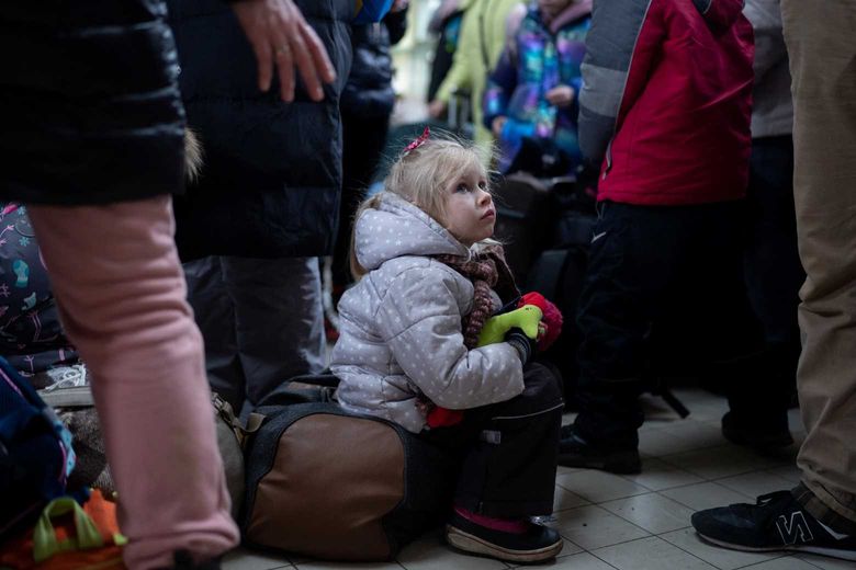 little girl looking sad as she waits for a train to escape the war in Ukraine