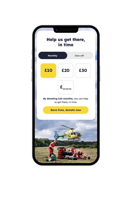 Mobile phone showing the SCAA donation page with monthly and one-off options, preset donation amounts, custom amount field, and a yellow ‘Save lives, donate now’ button above a photo of an air ambulance crew.