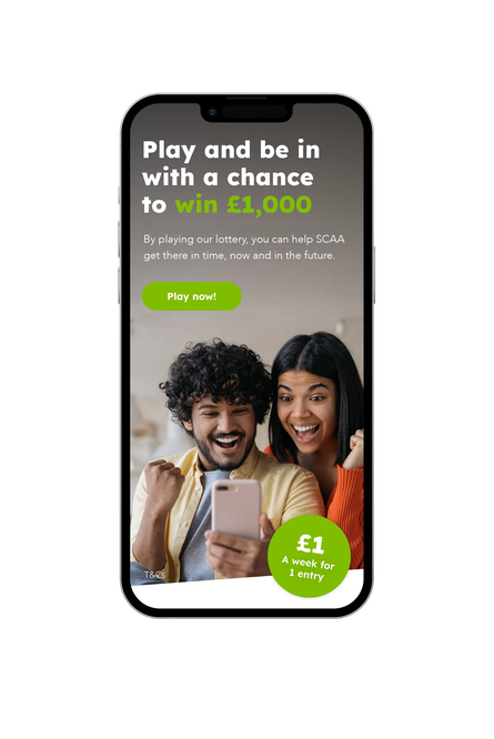 Mobile phone displaying SCAA lottery promotion with headline about winning £1,000, a green ‘Play now’ button, and a photo of two people celebrating while looking at a smartphone.
