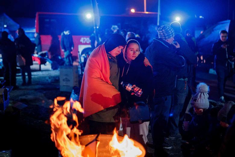 Ukrainian refugees keeping warm outdoors at night by an open fire