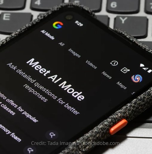 A smartphone screen displaying Google's AI Mode interface with the headline "Meet AI Mode" and example prompts, placed on top of a laptop keyboard.